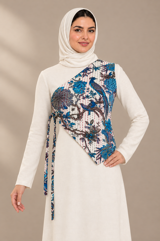 Evolving one-shoulder tie waistcoat, close front model view showing blue bird-and-floral print and right-side fabric ties; AI-styled visualization